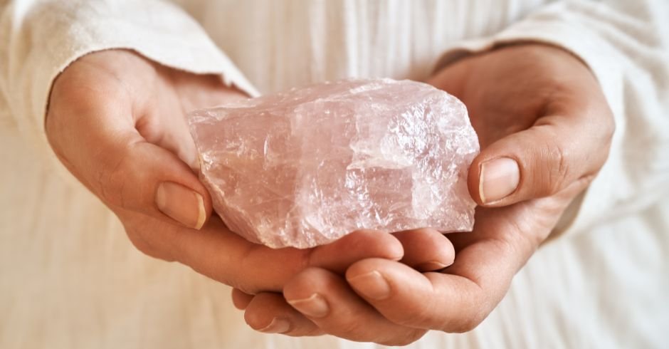 a crystal healing facial practioner carefully holding a rose quartz 