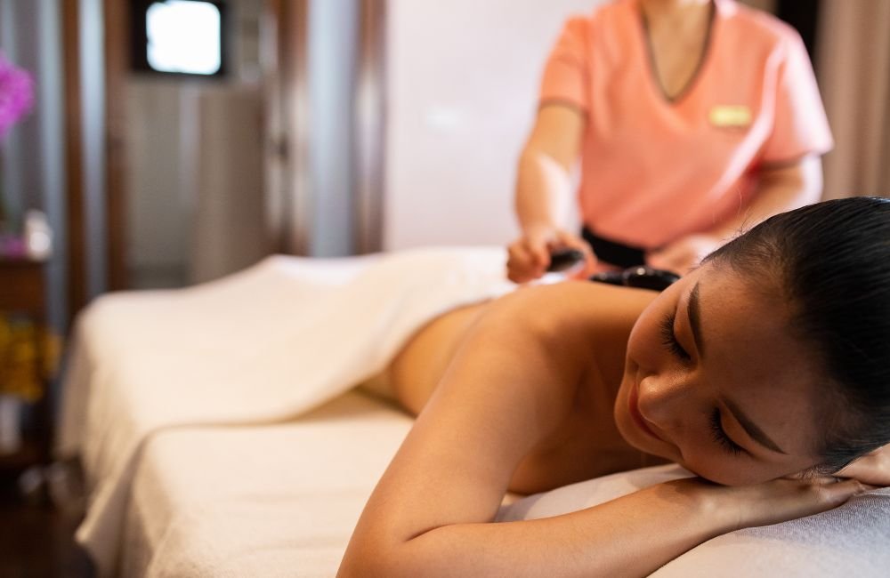 A young lady getting a hot stone massage to improve overall wellbeing, at Kiyora Spa, Chiang Mai, Thailand. 