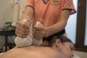 Spa therapist providing a guest a herbal compress massage, also used for burnout retreats for professionals in chiang mai. 