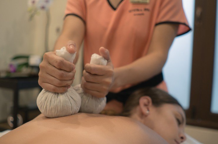 Spa therapist providing a guest a herbal compress massage.