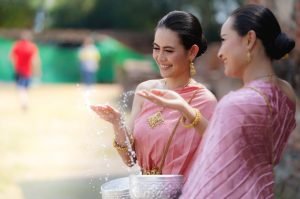 Celebrating Songkran in Chiang Mai 2023 with traditional water splashing. Two women show their respect by playfully splashing water on each other.