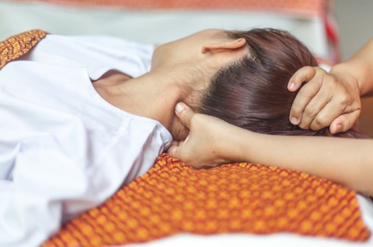 Traditional Thai Massage therapist applying acupressure on client.